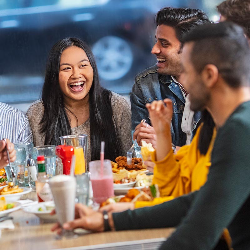A smiling group of friends enjoying a meal at a restaurant table